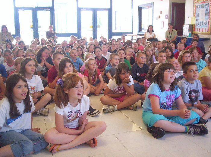 A packed room of children watching a Seeing Truth Ministry presentation